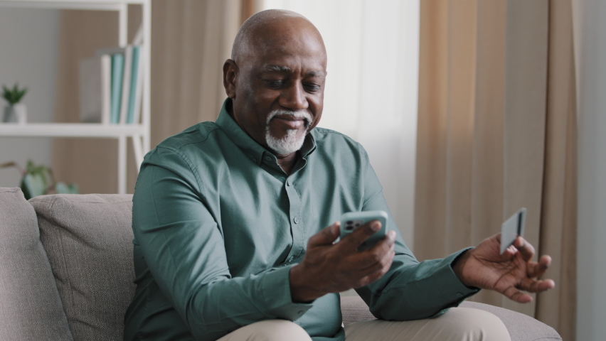 Confused puzzled senior African old bald senior elderly businessman with gray beard has problem with online payment upset retired man error in financial app smartphone money problem transfer at home Royalty-Free Stock Footage #1092722291