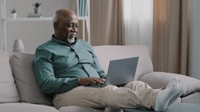 African bald overweight obese old middle-aged man senior businessman sitting on sofa at home working with laptop typing feels tired stress relaxing leaning back on sofa pauses after finishing work - Powered by Shutterstock - Get 15% off with code: PIKWIZARD15