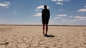 man walking in desert. aerial video of a barren, lifeless landscape. scarcity of water, dryland. global climate crisis, human footprint. cracked soil in a desert