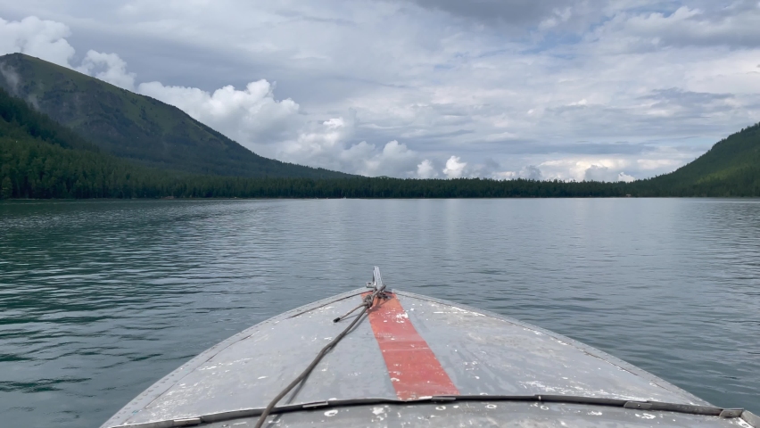 Motorboat on Multin lakes in middle of mountains under dramatic sky in Altai, Siberia, Russia. Beautiful summer nature landscape at pre storm daytime
