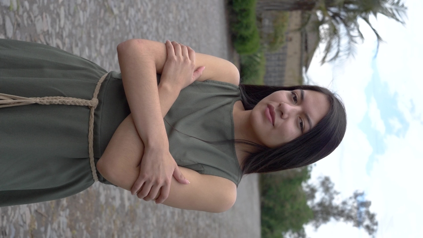 Beautiful Latino Hispanic long hair woman posing with green dress, outdoor vertical