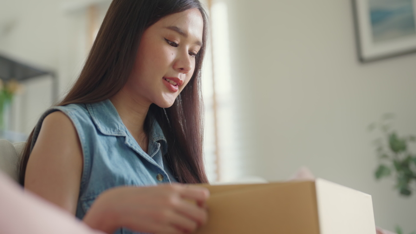 Young Gen Z influencer girl open gift postal mail box sit at home sofa couch. Asia people enjoy wow unbox carton parcel order online buy from small retail store SME shop supply chain omni channel. | Shutterstock HD Video #1092732865