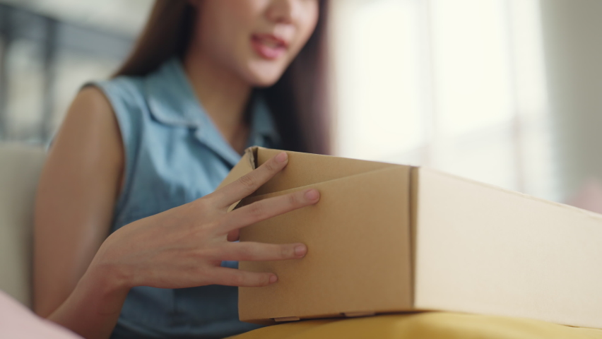 Young Gen Z influencer girl open gift postal mail box sit at home sofa couch. Asia people enjoy wow unbox carton parcel order online buy from small retail store SME shop supply chain omni channel. | Shutterstock HD Video #1092732869