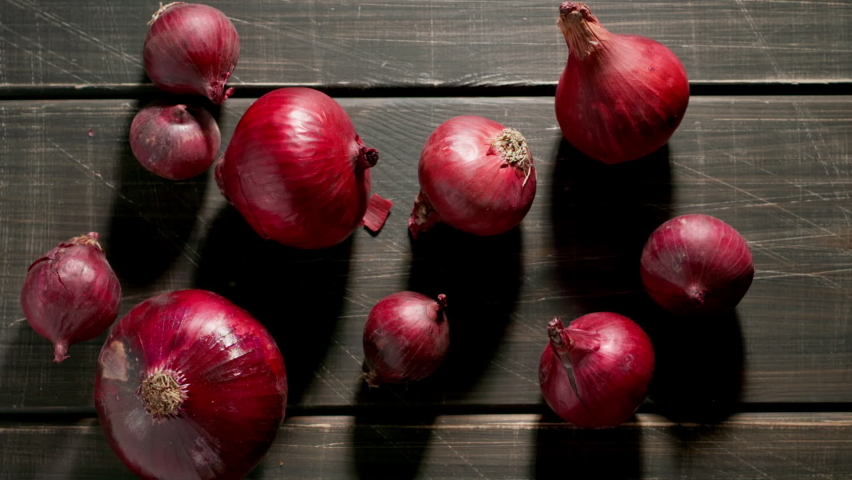 TOP VIEW: Peels fall on a red onion bulbs on a wooden dark table