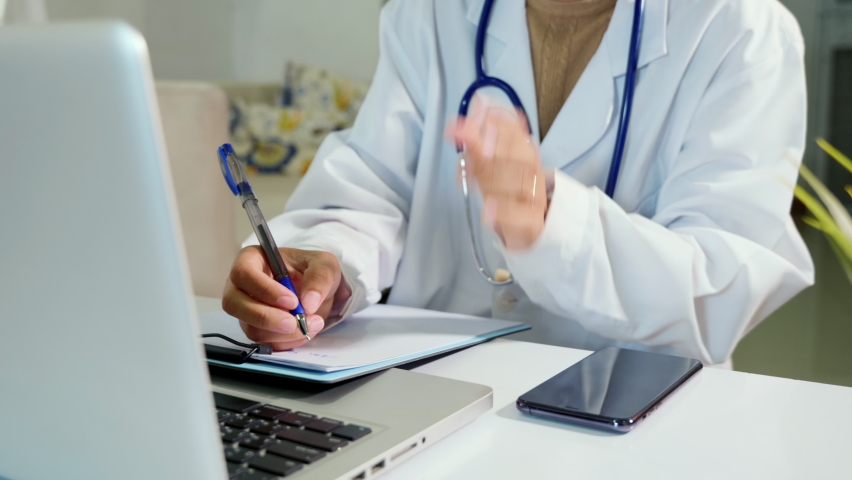 Closeup of doctor or nurse woman in uniform with stethoscope writing information of patient prescription in paperwork on clipboard and typing laptop computer for history record medical document report Royalty-Free Stock Footage #1092742011