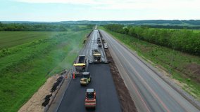 Road construction works view from a height. Laying of new asphalt. The paver lays fresh asphalt, road rollers level and compact asphalt. Road construction equipment, view from a height - Powered by Shutterstock - Get 15% off with code: PIKWIZARD15