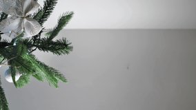 A person decorates a Christmas tree and tries to put a star on the top of the tree. vertical video