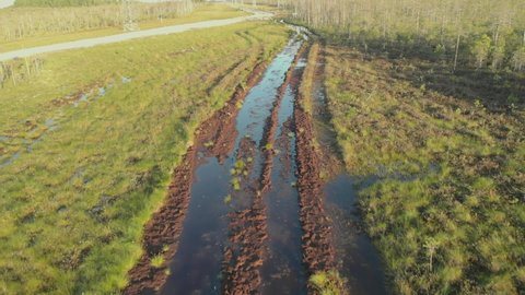 The drone flies over a broken road in the swamps of Siberia, on which only all-terrain vehicles can move. The swamps of Russian Siberia with a large supply of minerals are easily accessible