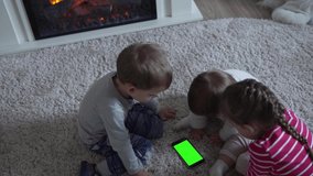 Adorable Cheerful Lucky Smart Joyful Toddler Children On Carpet Using Smartphone Green Screen Mobile Phone Hromakey Watching Videos Relaxing At Home Cartoons Play Internet Games. Kids Enjoy Learning