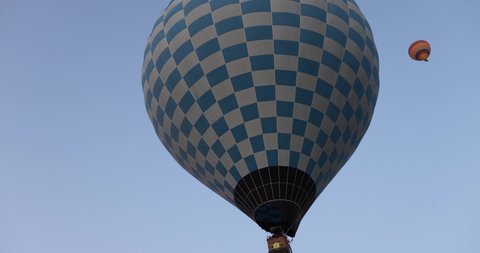 A hot air balloon with a basket flies across the evening sky.