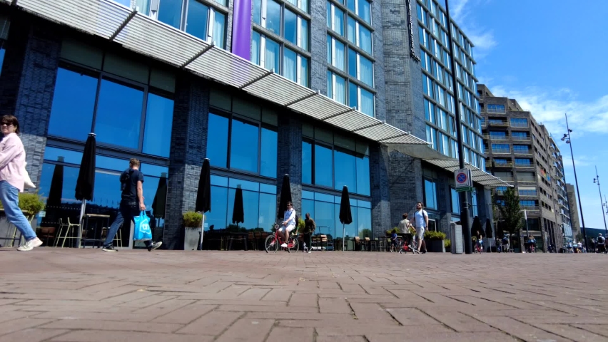 Timelapse. Crowded street of Amsterdam. People walk down the street on a sunny day, near the river.