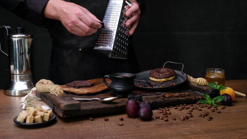 Cook prepares, chocolate on a grater. Close-up video shooting, dark background
