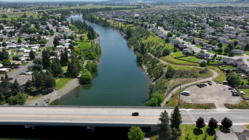 Lone car driving over a bridge crossing the Spokane River.