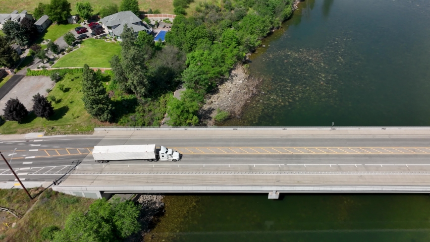 Aerial shot of a semi truck crossing a bridge that passes over a river in Washington State. Royalty-Free Stock Footage #1092782527