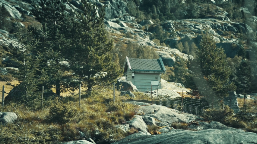 A tiny hut hidden in the mountains. Slow-motion, pan right.
