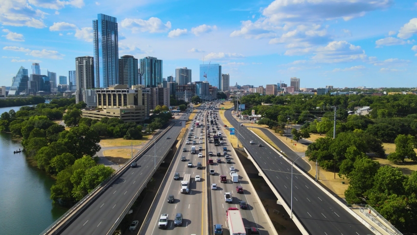 Rush hour traffic with the city in the background. The drone remains still while traffic flows underneath it.