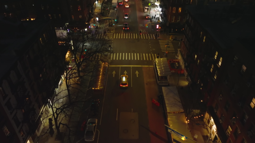 Forwards tracking of typical yellow cab driving through streets of night city. High angle view of taxi passing road intersection. Manhattan, New York City, USA