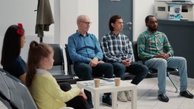 Diverse group of people sitting together in hospital waiting room, preparing to meet with general practitioner at medical clinic. Different patients waiting to attend appointment. Tripod shot. - Powered by Shutterstock - Get 15% off with code: PIKWIZARD15