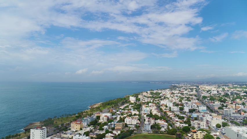 City on the Caribbean coast, aerial view. Houses and roads along the coastline of the ocean. Modern buildings of the old city. Santo Domingo, Dominican Republic - June 15, 2022. Royalty-Free Stock Footage #1092799609