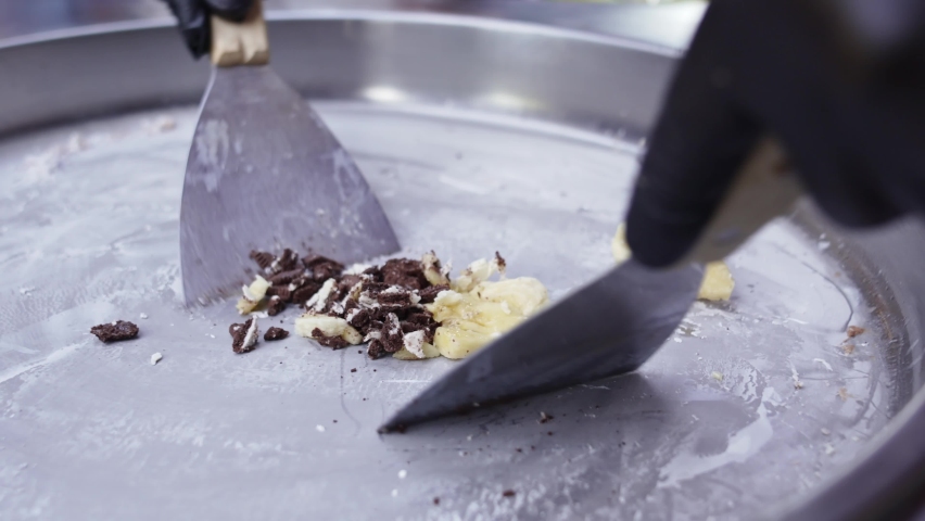 Gloved hands make roll ice cream for an outdoor party. a refreshing sweet dish made from natural fresh fruits and berries with the addition of sugar syrup.