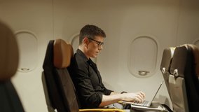 4K Caucasian businessman passenger sitting in airplane and working on laptop computer with wifi internet. Commercial Airline service business and global transportation concept. - Powered by Shutterstock - Get 15% off with code: PIKWIZARD15