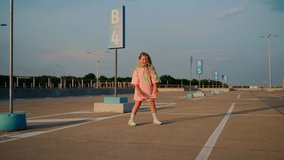 Girl dancing at parking outdoors. Professional child dancer express positive emotions using her body. Young female person with green afro braids moving on music. Carefree childhood. Slow motion 4K