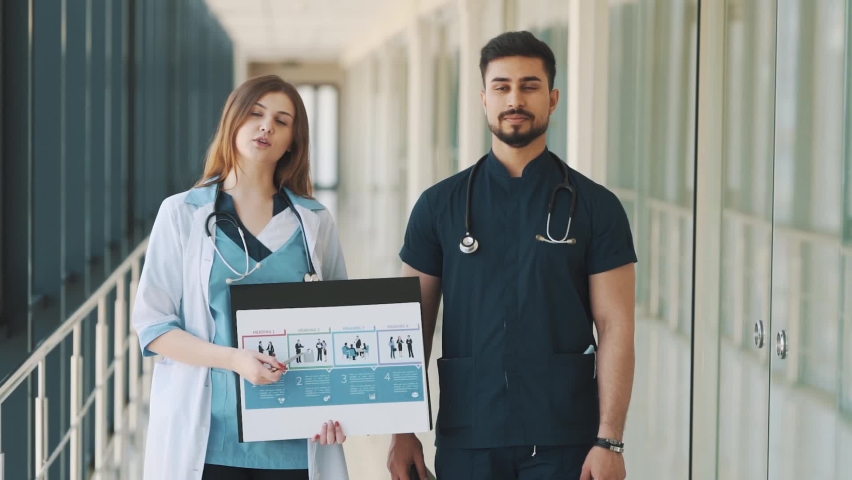 Portrait of a doctor and a nurse giving an online presentation in a hospital corridor | Shutterstock HD Video #1092818275