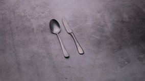 Serving dishes on the table, spoon and knife, cutlery video on a dark background