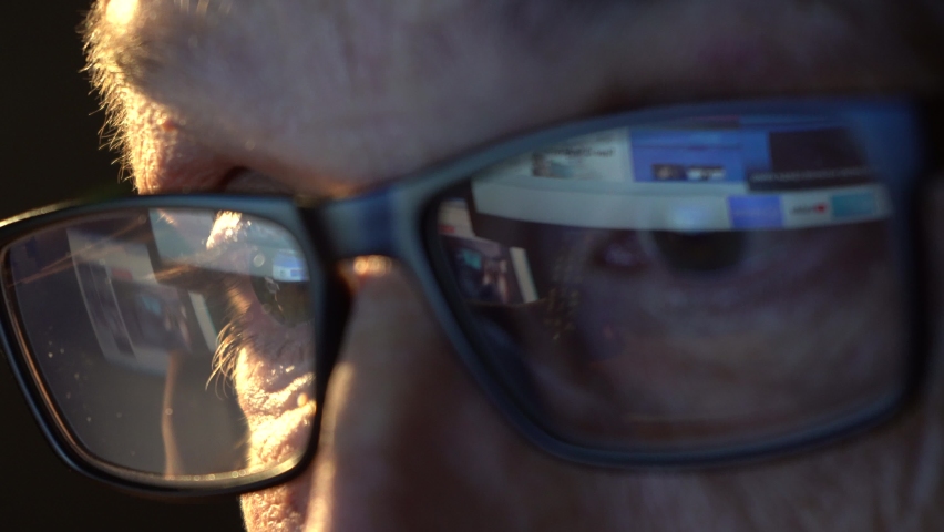 Close-up of the focused eyes of a businessman wearing computer glasses, looking at a reflective PC screen Royalty-Free Stock Footage #1092823721