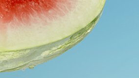 a sliced red watermelon against a blue sky, water dripping from it. Slow mo - Powered by Shutterstock - Get 15% off with code: PIKWIZARD15