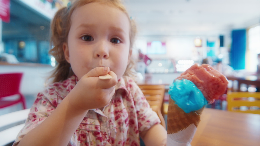 Toddler girl eats ice cream in a cafe. Crash zoom effect