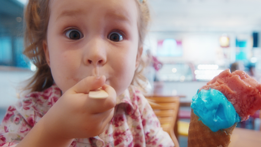 Toddler girl eats ice cream in a cafe. Crash zoom effect