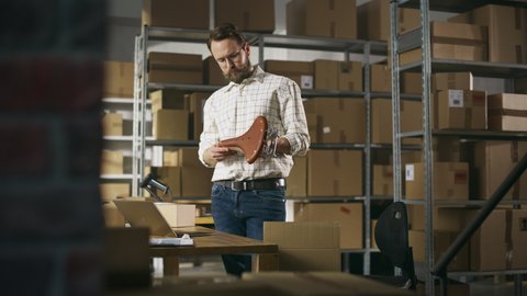 Small Business Owner Packaging a Retro Bicycle Seat Sold to a Client Online. Preparing a Small Cardboard Box for Postage. Stylish Male Inventory Manager Working in Warehouse Facility.: film stockowy