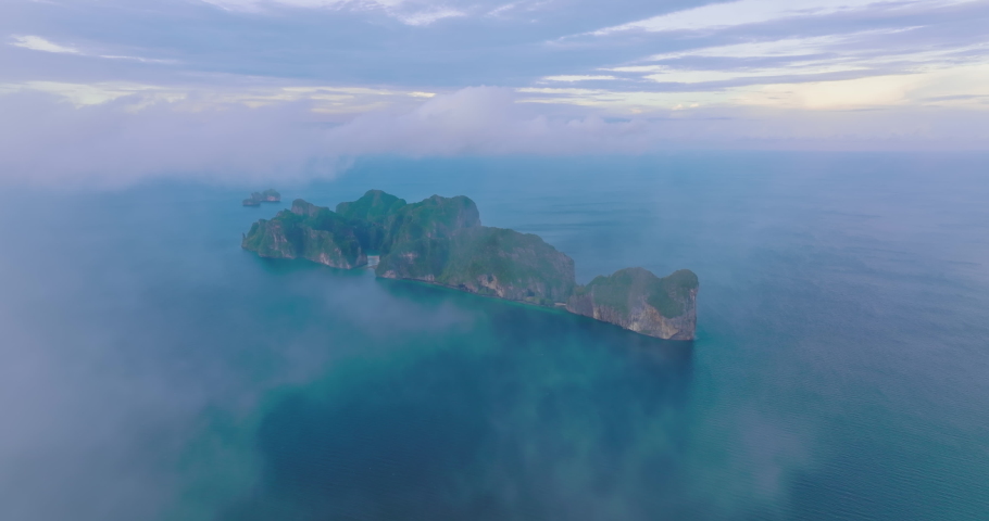 Aerial view of Phi Phi islands covered with fog tourist attraction travel landmark of Krabi, Thailand. Drone shot coming out from a thin cloud over Maya beach with beautiful blue turquoise seawater. | Shutterstock HD Video #1092831571