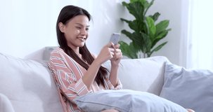 Asian  woman using smartphone in living room at home.