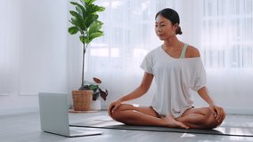 Athletic asian woman performs Meditate pose on yoga mat to strong stretching to exercise at home. female body muscle and  training fitness indoors. Healthcare with yoga therapy and sports concept