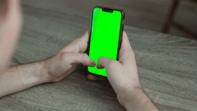 Man using a mobile phone with chroma key green screen, watching a video or having an online conference - technology, communications concept close up 4k video template
