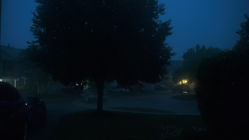 Hard storm, rain with loud thunder and lightning, a suburban residential street at night time. 