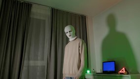 Gangster in a white mask for a rap video. A young guy is dancing in an ultraviolet neon room.
