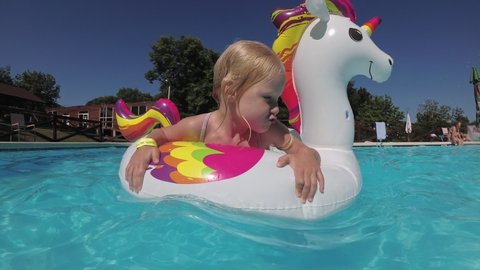 Happy child girl swims in a large inflatable circle in a summer outdoor pool