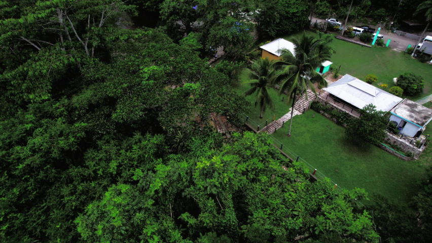 Aerial shoot of wharf next to rain forest and brown river with bamboo rafts in Jamaica