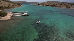 Slow drone helix around small boat. Exploring a beautiful turquoise lagoon in the Kornati National Park, in Croatia by motorboat. Shallow bay in the Mediterranean Sea on a hot summer day.