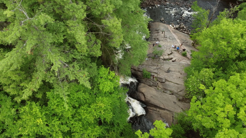 Birds eye view drone fly around arrowhead provincial park capturing beautiful Stubb’s Falls with people resting on rock, enjoying the pleasant natural environment, Huntsville, Ontario, Canada.