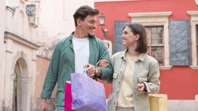 Portrait of cheerful Caucasian young couple man and woman holding many paper bags after shopping while walking and talking on street. Happy family couple with packages outdoor. Buying concept - Powered by Shutterstock - Get 15% off with code: PIKWIZARD15