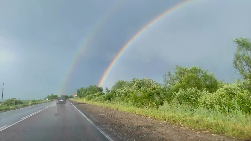 drive in the car in the rain during daylight hours. rainbow from the car window