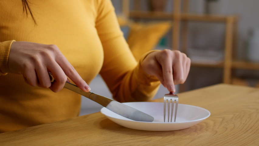 Food crisis concept. Close up shot of unrecognizable woman eating invisible meal, using cutlery in empty plate, slow motion, free space Royalty-Free Stock Footage #1092869055