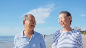 Asian senior older couple walking on the beach during summer together. Elderly mature grandparents traveler feeling happy and relax while travelling for a holiday vacation trip in tropical sea island. - Powered by Shutterstock - Get 15% off with code: PIKWIZARD15