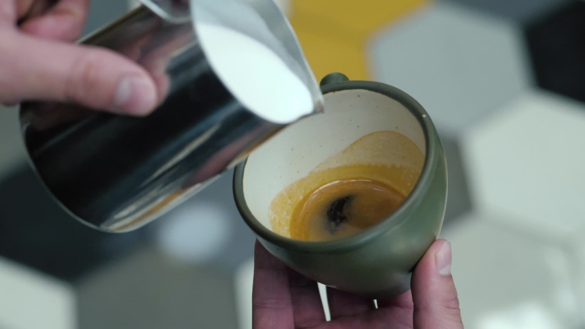 Milk being poured into a mug with coffee, creating latte art | Shutterstock HD Video #1092872699