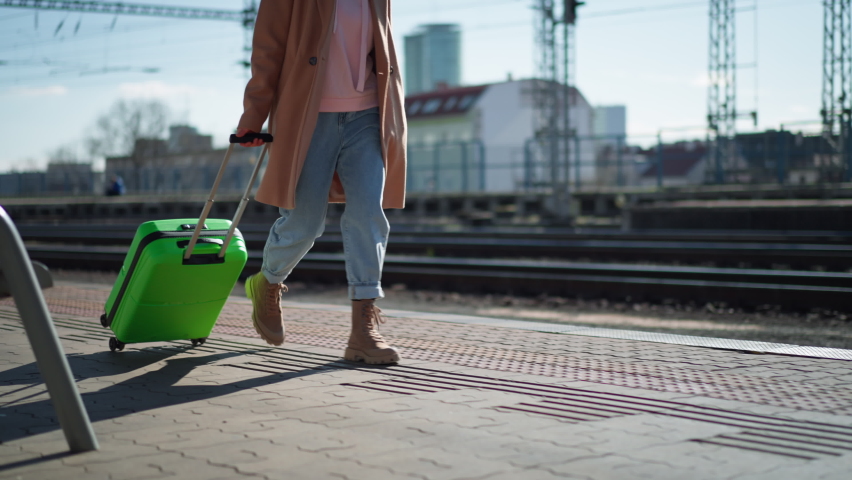 Woman traveler tourist going trough station with luggage, side view.
