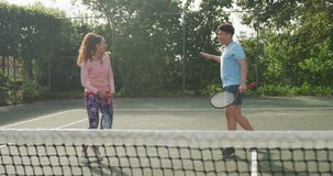 Video of happy biracial couple playing tennis on the court. Healthy active lifestyle and fitness at home.